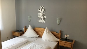 A neatly made bed with white linens, two bedside tables with lamps, and a motivational quote on the wall. - Hotel zur Pfalz (Hockenheim)
