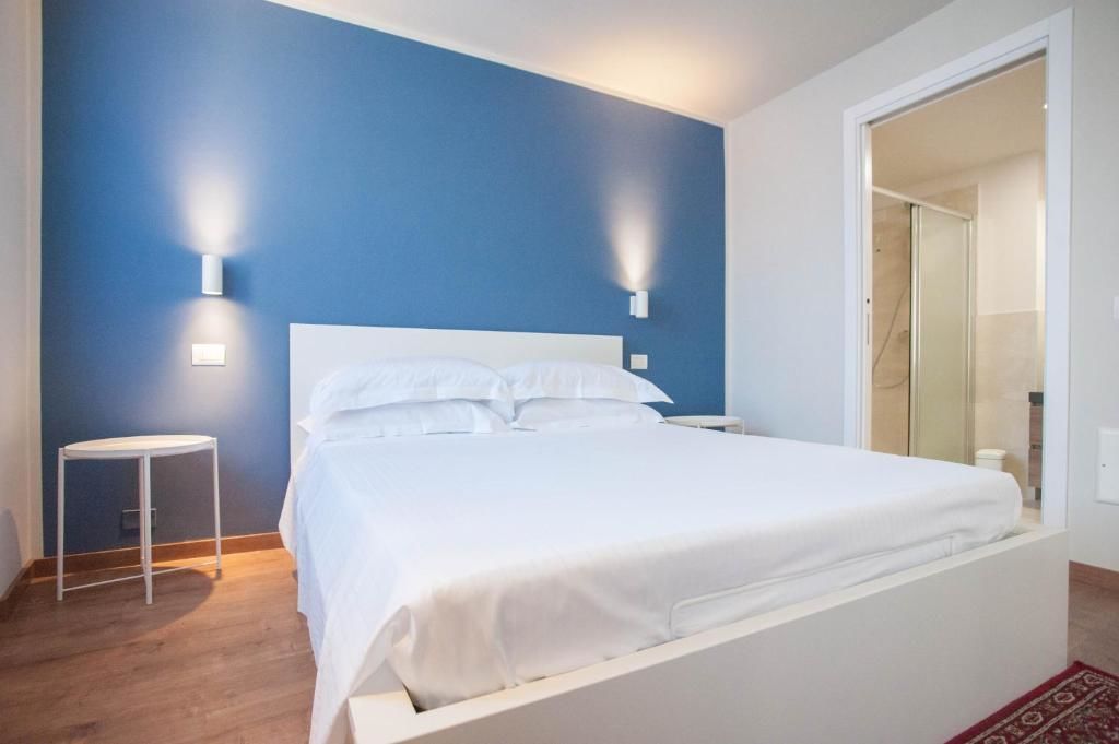 A bedroom with a bed, two wall-mounted lights, a small table, and a door leading to a bathroom.