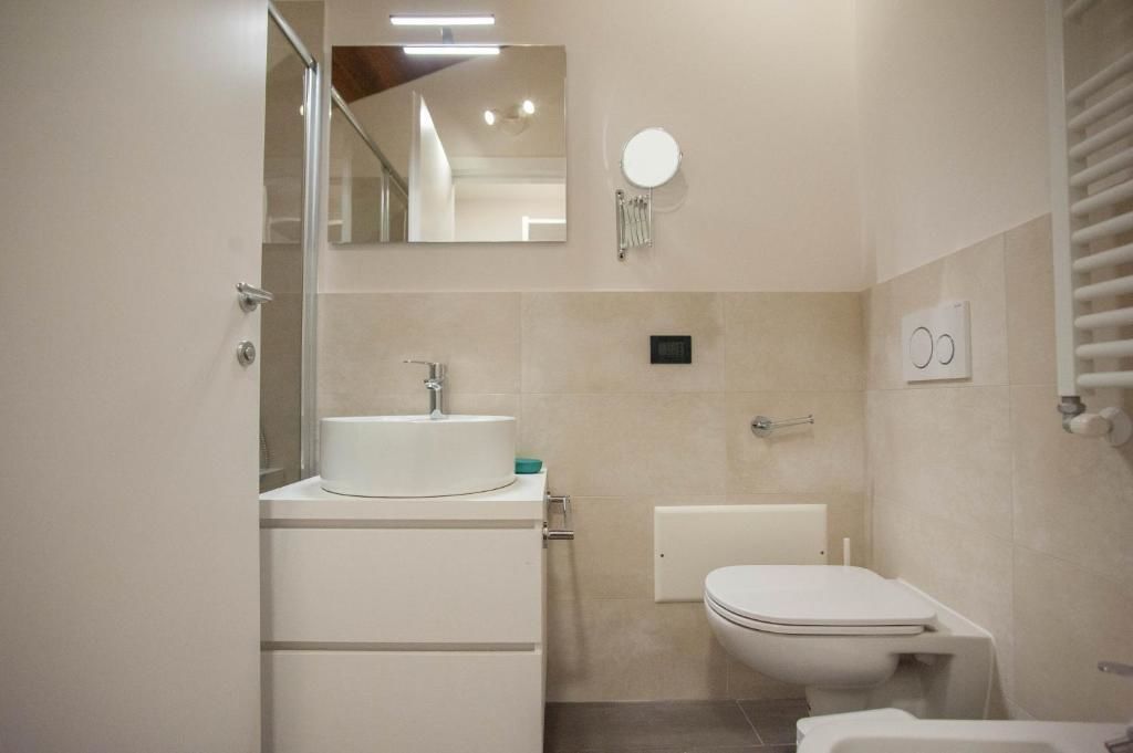 A modern bathroom with a white sink, a toilet, and a mirror.