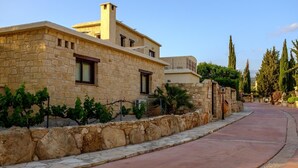 A stone building with a paved walkway and a stone wall. - Villa Anemona (Pegeia)