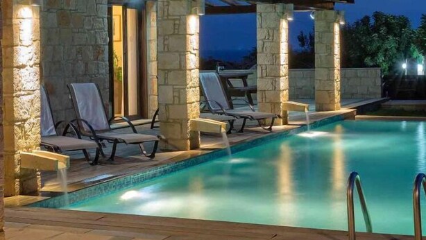 A pool area with stone pillars, lounge chairs, and a pergola structure. - Villa Anemona (Pegeia)