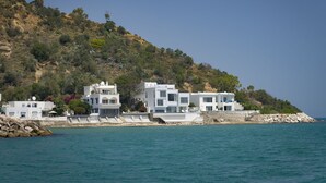 A coastal building with a stone retaining wall and a clear view of the sea.