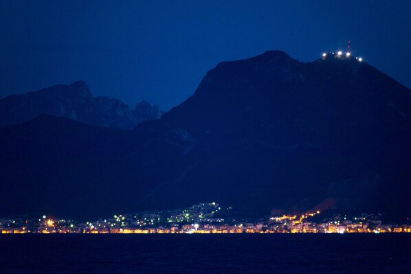 A coastal city at night with a mountain in the background.