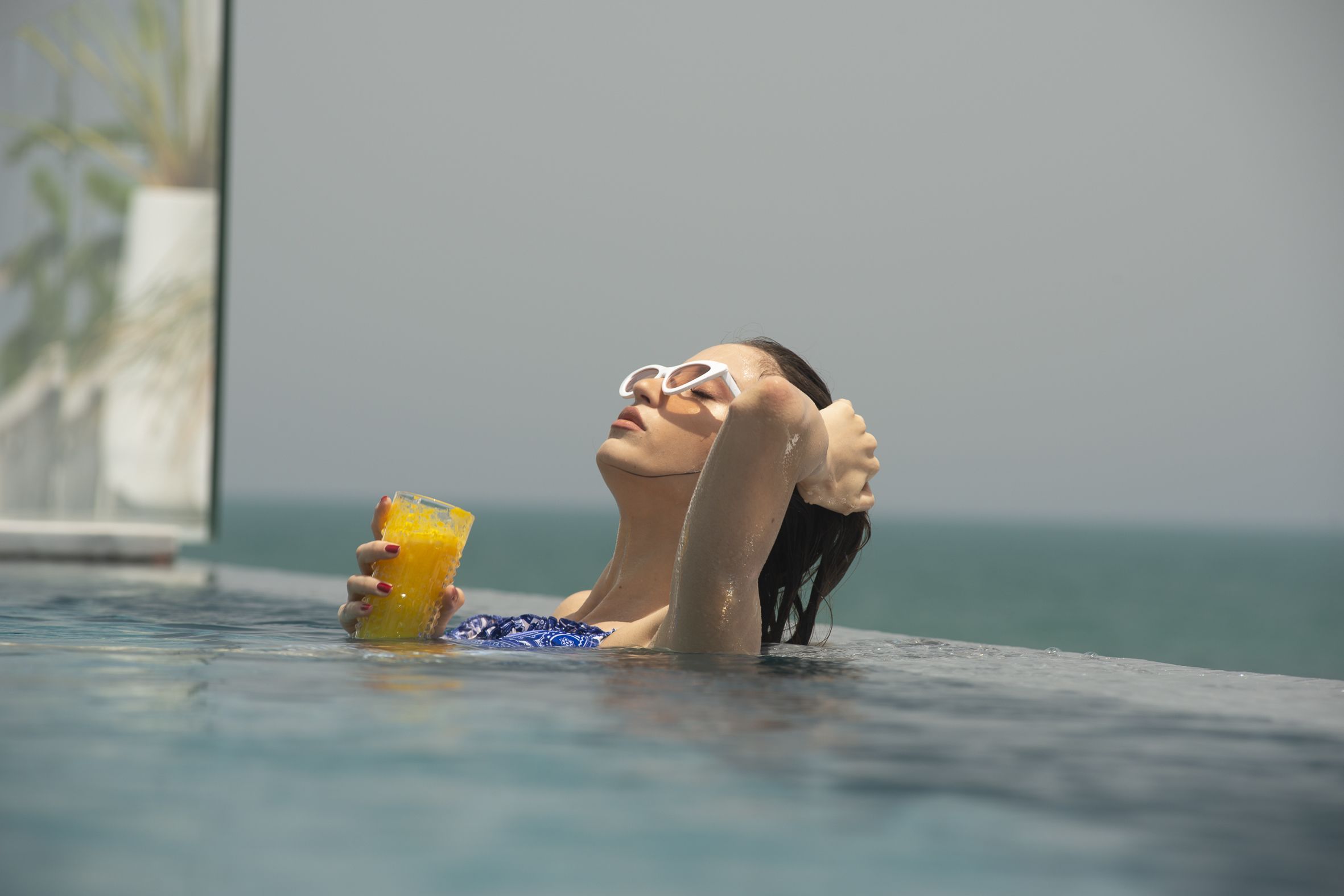 Una persona relajándose en una piscina con una bebida.
