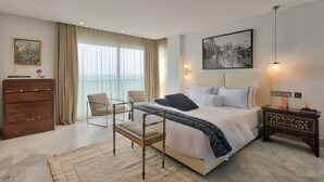 A modern hotel room with a large bed, a chair, a dresser, and a view of the city through the window.