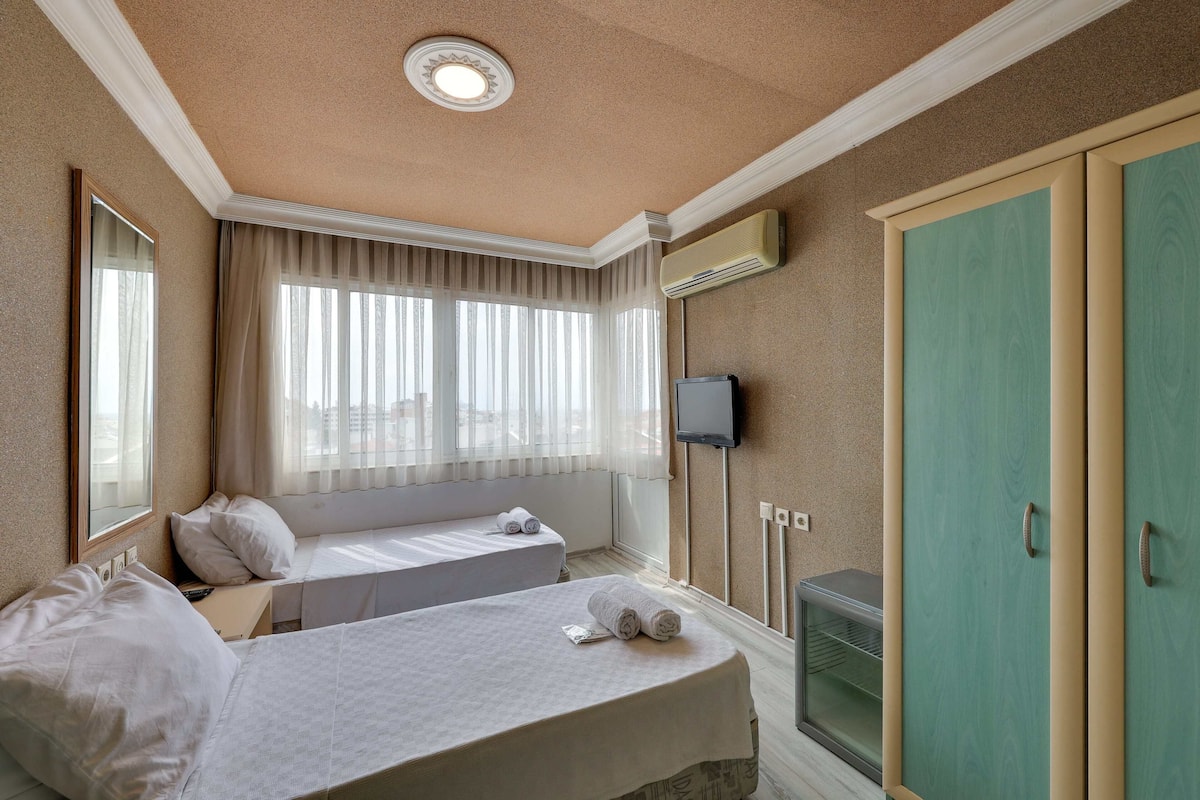 A hotel room with two beds, a television, and a wardrobe.