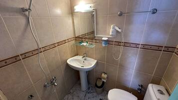 Um banheiro com pia, vaso sanitário e chuveiro.