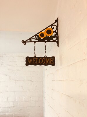 A wall-mounted sign with a sunflower and the word "WELCOME". - Hurst Cottage (Hassocks)