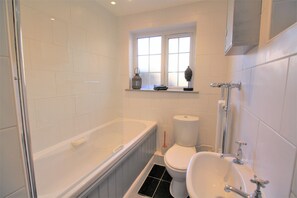 A bathroom with a bathtub, toilet, and sink. - Hurst Cottage (Hassocks)