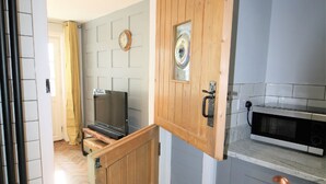 Une cuisine avec une porte en bois, un four à micro-ondes et un téléviseur.