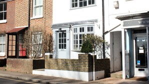 Une rangée de maisons mitoyennes aux façades en briques et peintes en blanc, avec une porte bien visible et un petit jardin.