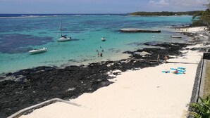 A beach with clear turquoise water, rocky areas, and a sandy shore. - Blue Beryl Guest House (Blue Bay)