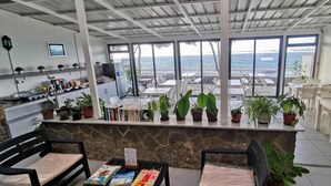 A restaurant with a stone counter, potted plants, and a view of the sea. - Blue Beryl Guest House (Blue Bay)