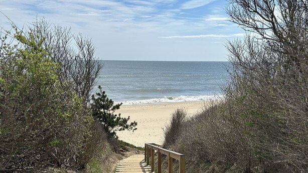 A wooden staircase leading to a beach with a clear view of the ocean.