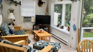 A cozy living room with wooden furniture, a flat-screen TV, and a skylight.