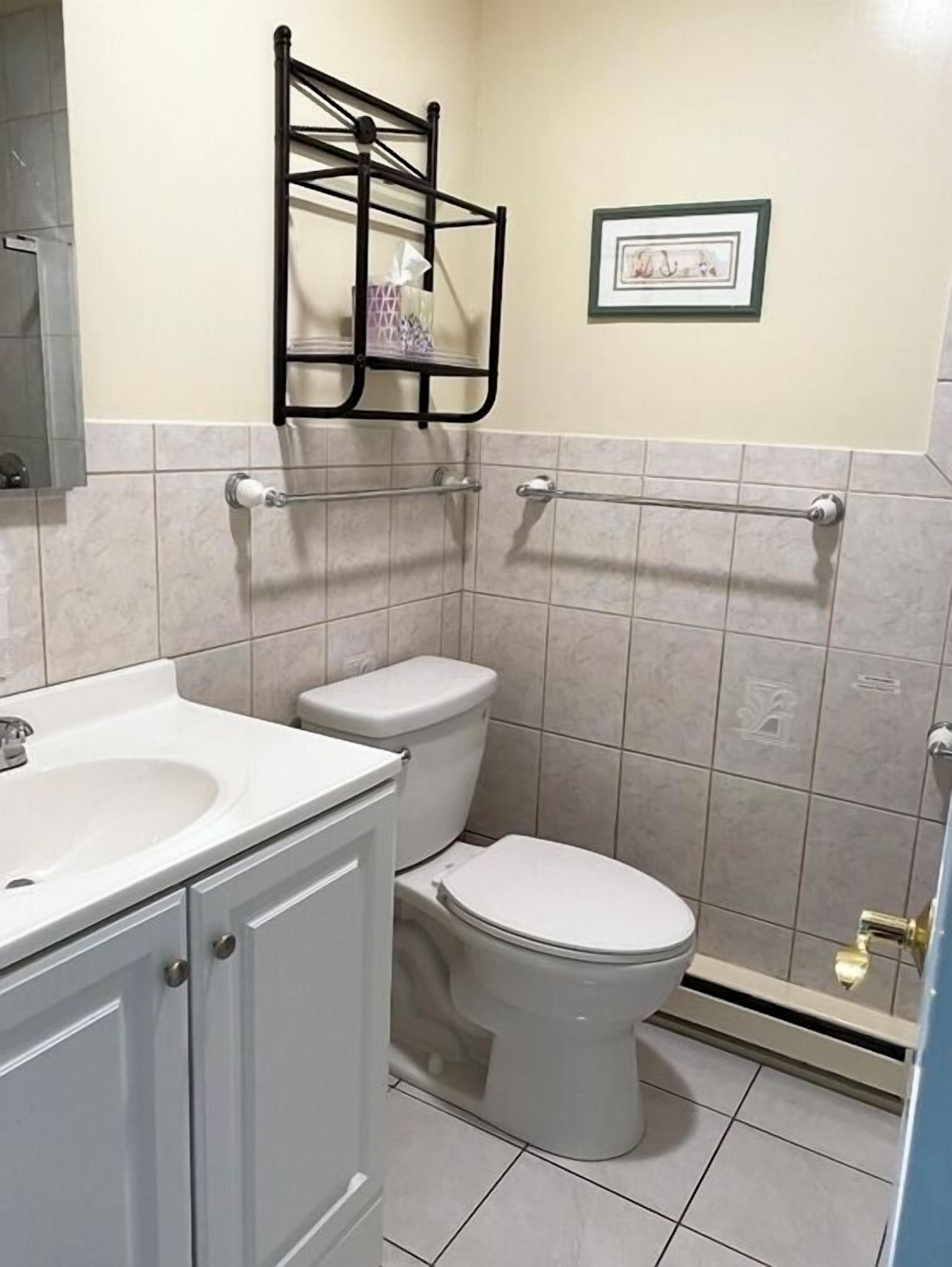 A bathroom with a toilet, sink, and a towel rack.
