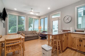 A modern kitchen with wooden cabinets, a dining table, and a bar area.