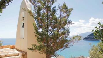 A coastal view with a white bell tower, steps leading down, and a tree in the foreground.
