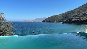 A clear view of a swimming pool with a view of the sea and a distant mountain range.