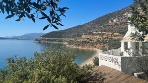 A coastal view with a white building, a clear blue sky, and a calm sea.