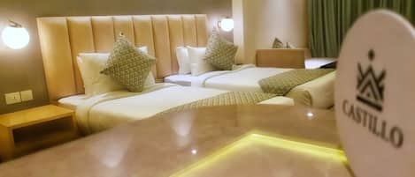 Una habitación de hotel con dos camas, una mesita de noche y otra mesa auxiliar.