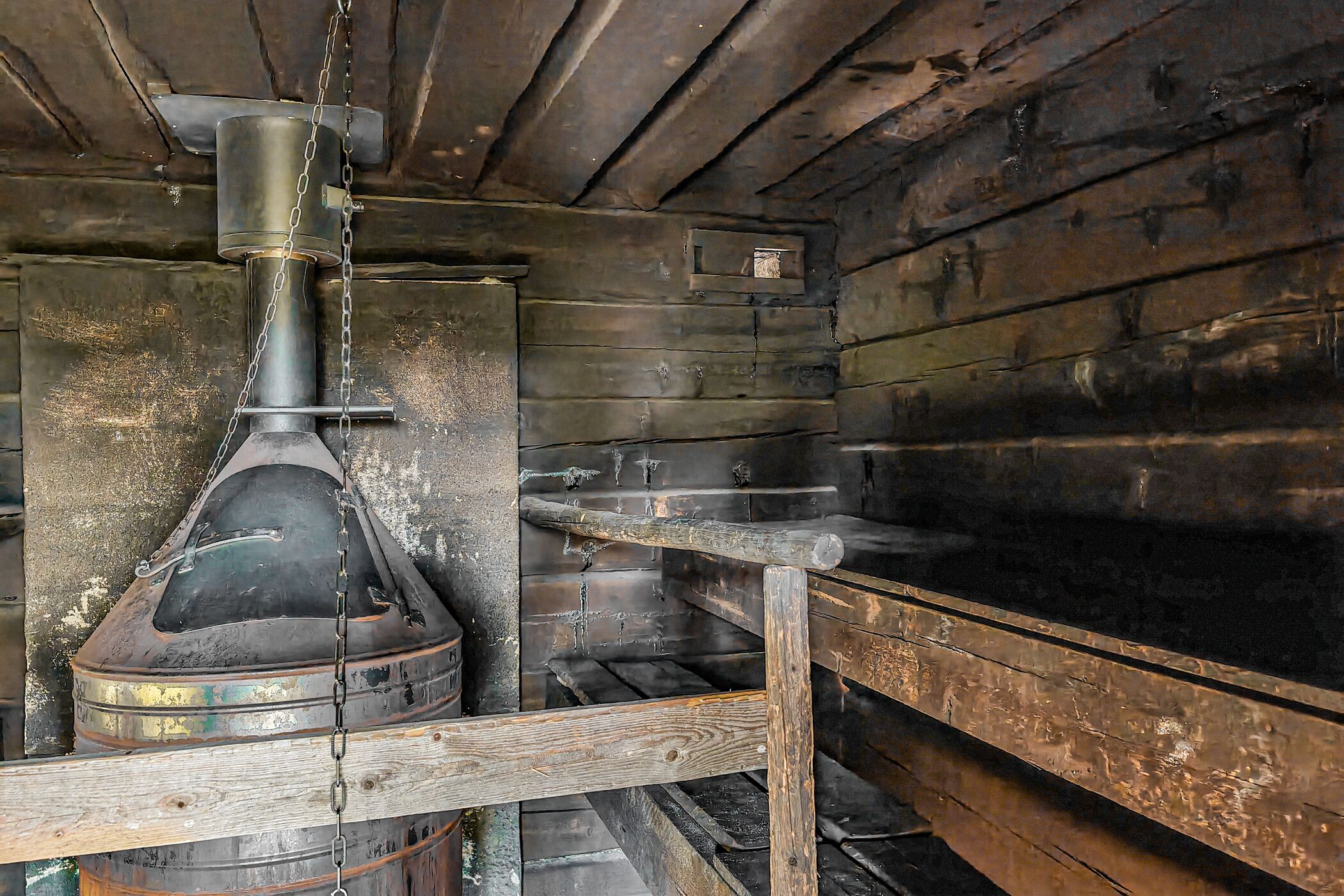 A rustic wooden interior with a metal chimney, wooden shelves, and a small metal box.