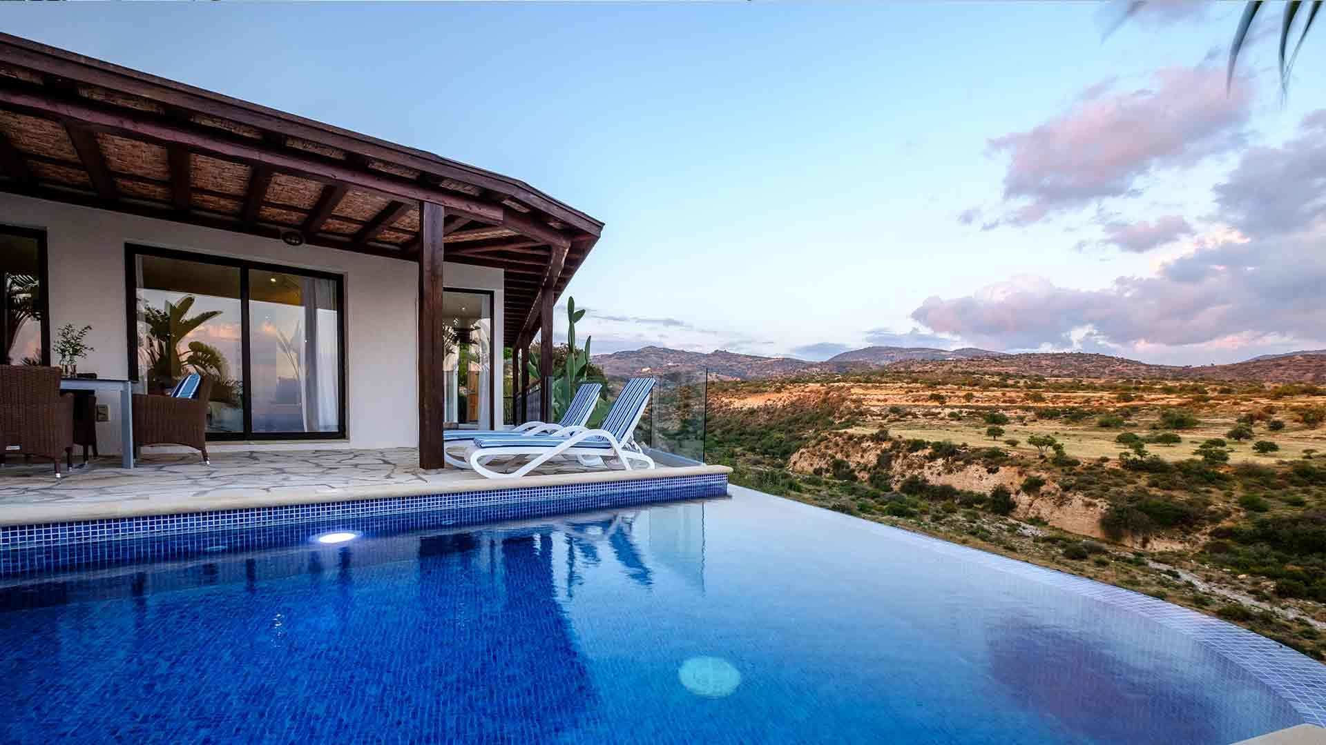 Una piscina al aire libre, sombrillas, sillones reclinables de piscina