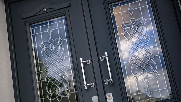 A black door with two glass panels, each featuring a geometric pattern.