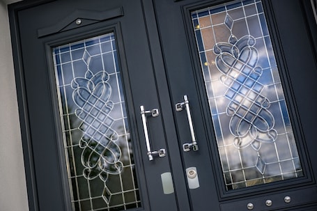 A black door with two glass panels, each featuring a geometric pattern.
