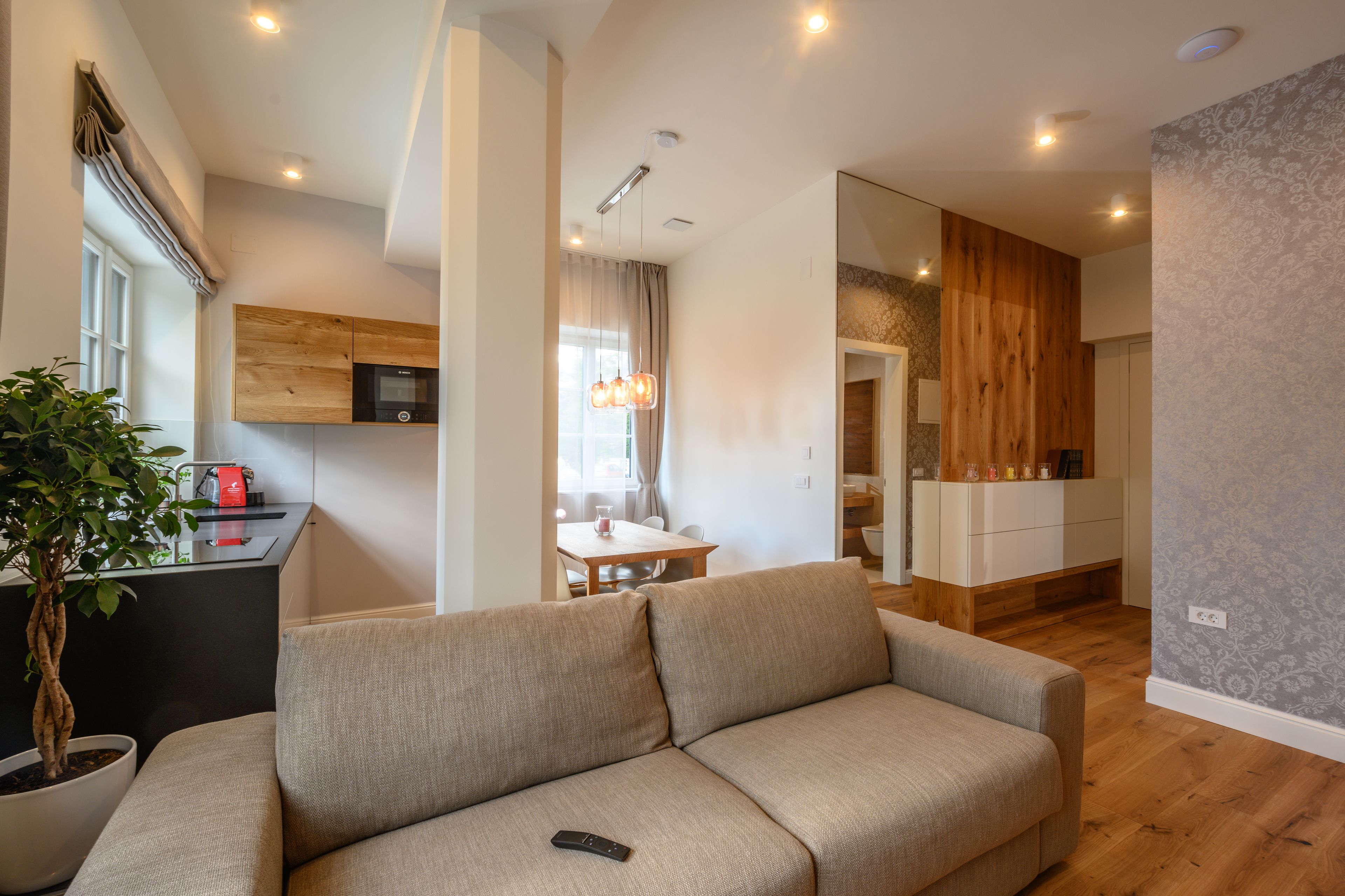 A modern living room with a sofa, a dining area, and a kitchen.