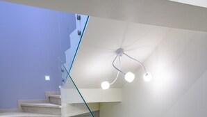 A modern staircase with glass railings and recessed lighting.