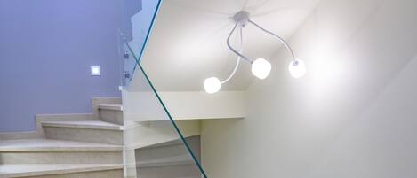 A modern staircase with glass railings and recessed lighting.