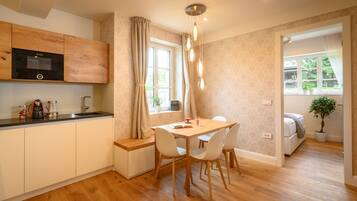 A modern kitchen with wooden cabinets, a built-in microwave, and a dining area with a table and chairs.