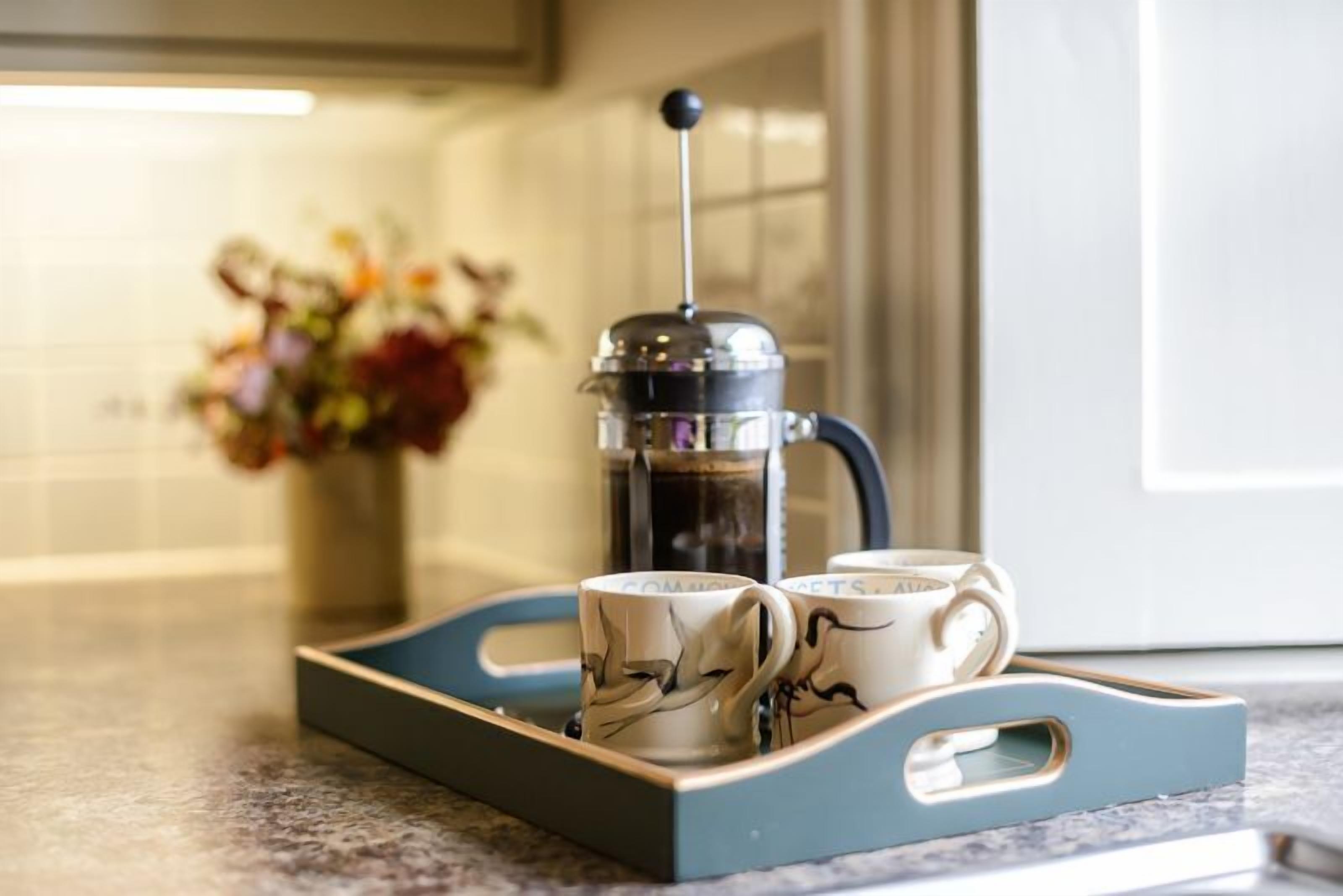 Une cafetière à piston français sur un comptoir de cuisine, avec deux tasses à café.
