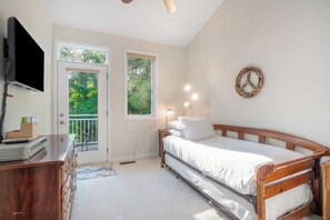 Ein Schlafzimmer mit Bett, Schminktisch, Fernseher, einer zur Balkontür führenden Tür und einem an der Wand befestigten Friedenssymbol.