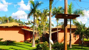 A hotel with a red facade, palm trees, and a clear sky. - Estancia Park Hotel (Anapolis)