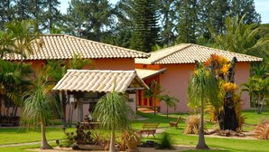 A house with a tiled roof, surrounded by a well-maintained garden with palm trees and other plants. - Estancia Park Hotel (Anapolis)