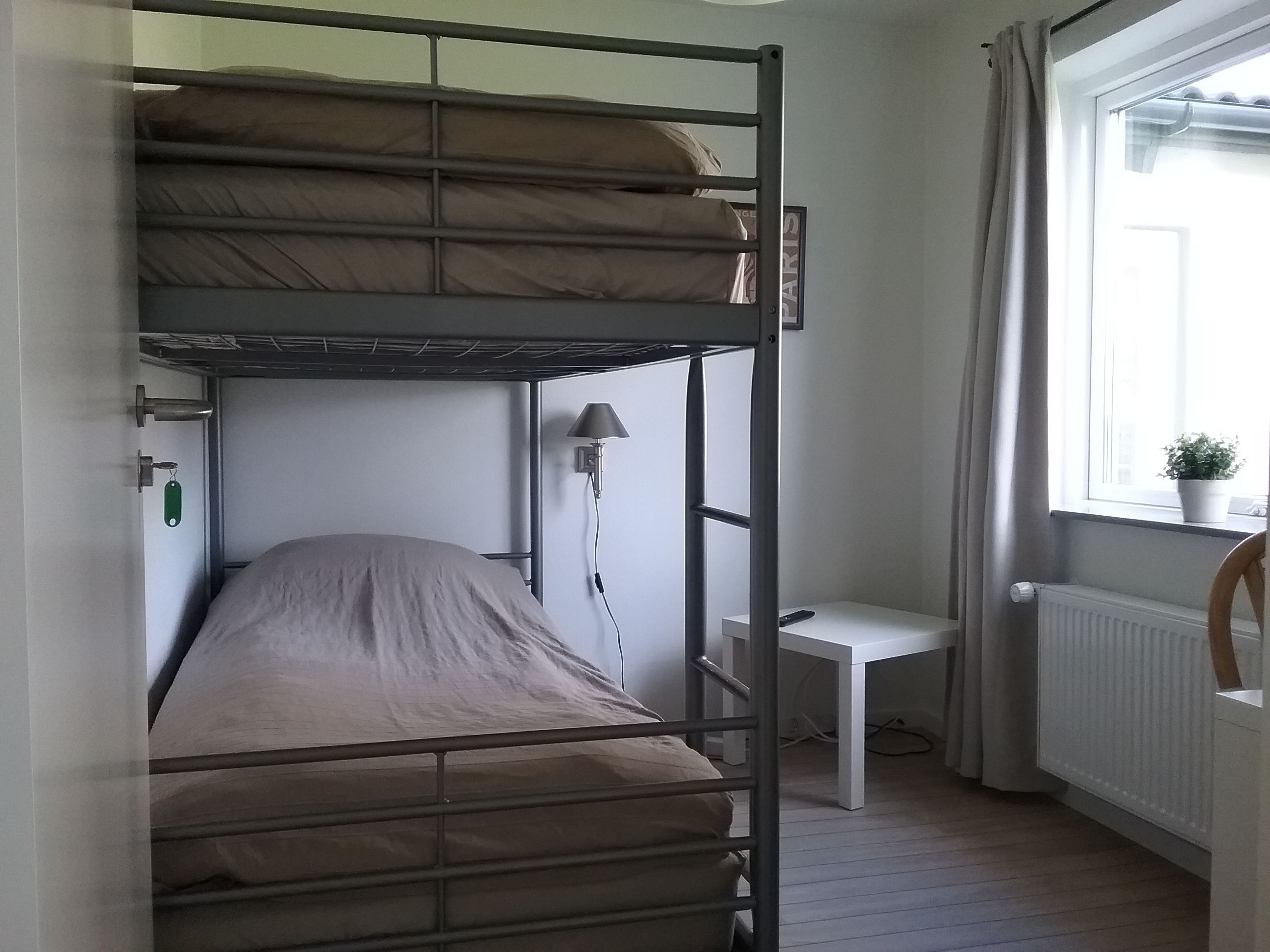 A bunk bed room with a desk and a radiator.