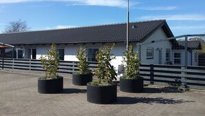 A building with a tiled roof, a fenced area with potted plants, and a street lamp. - Hals Hotel Apartment (Hals)