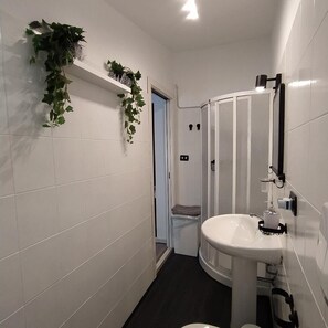 A bathroom with white tiled walls, a white sink, a mirror, and a shower enclosure. - Romantic historic house in Atri with a view of the Gran Sasso - CIN IT067004C2D739CXUO (Atri)
