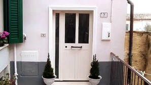 A white door with a small window, a number '7' sign, and two potted plants on either side. - Romantic historic house in Atri with a view of the Gran Sasso - CIN IT067004C2D739CXUO (Atri)