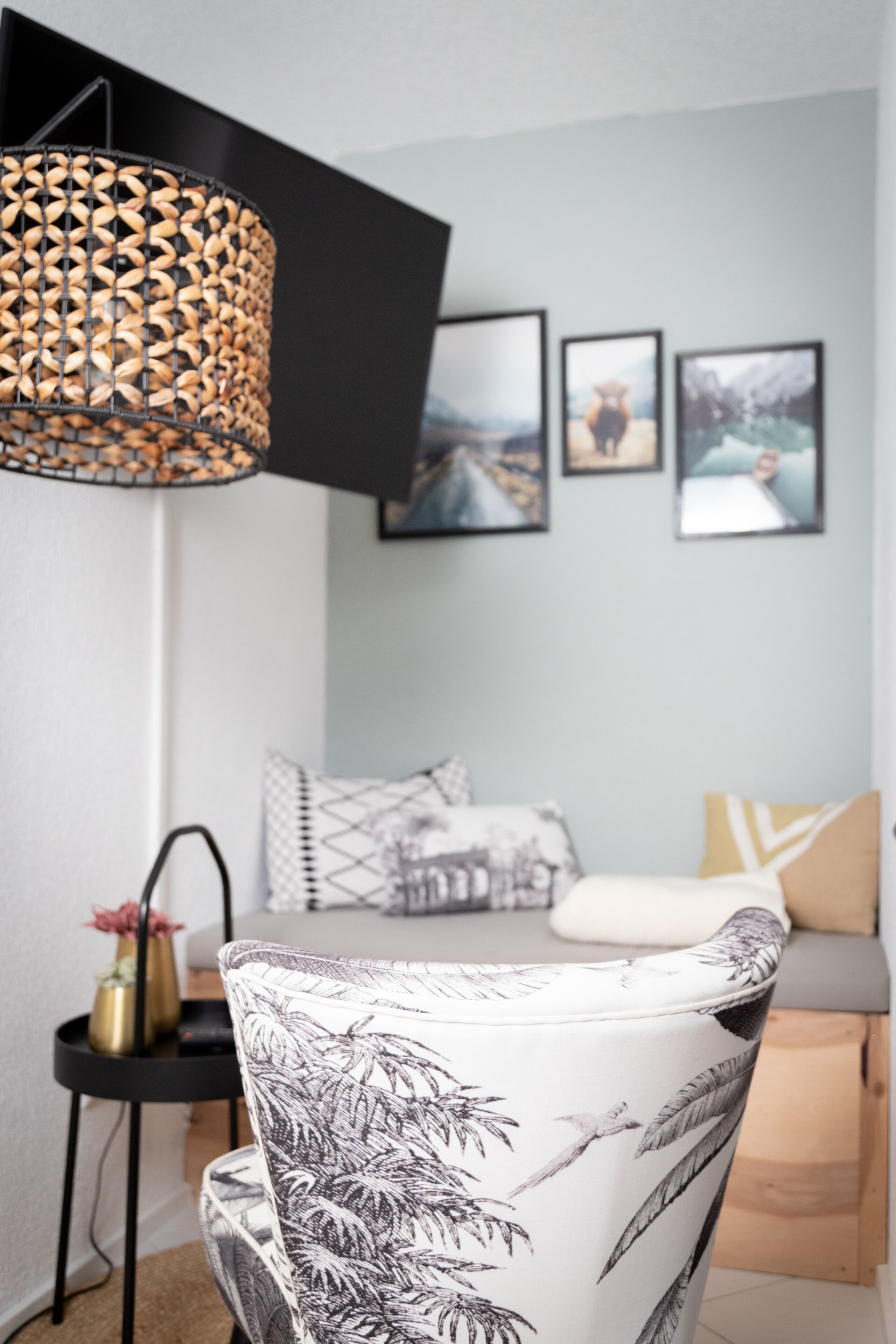 Un soggiorno moderno con un divano, una poltrona con motivi decorativi, una lampada da terra e opere d'arte appese al muro.