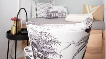 Un soggiorno moderno con un divano, una poltrona con motivi decorativi, una lampada da terra e opere d'arte appese al muro.