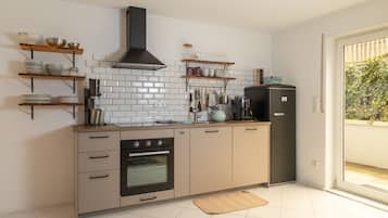 Una cucina moderna con zoccolo di piastrelle bianche, ripiani in legno e forno integrato.