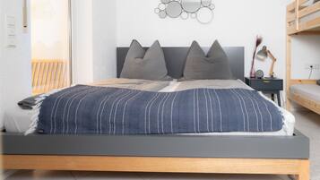 A modern bedroom with a bed, bedside tables, and a wall-mounted mirror.