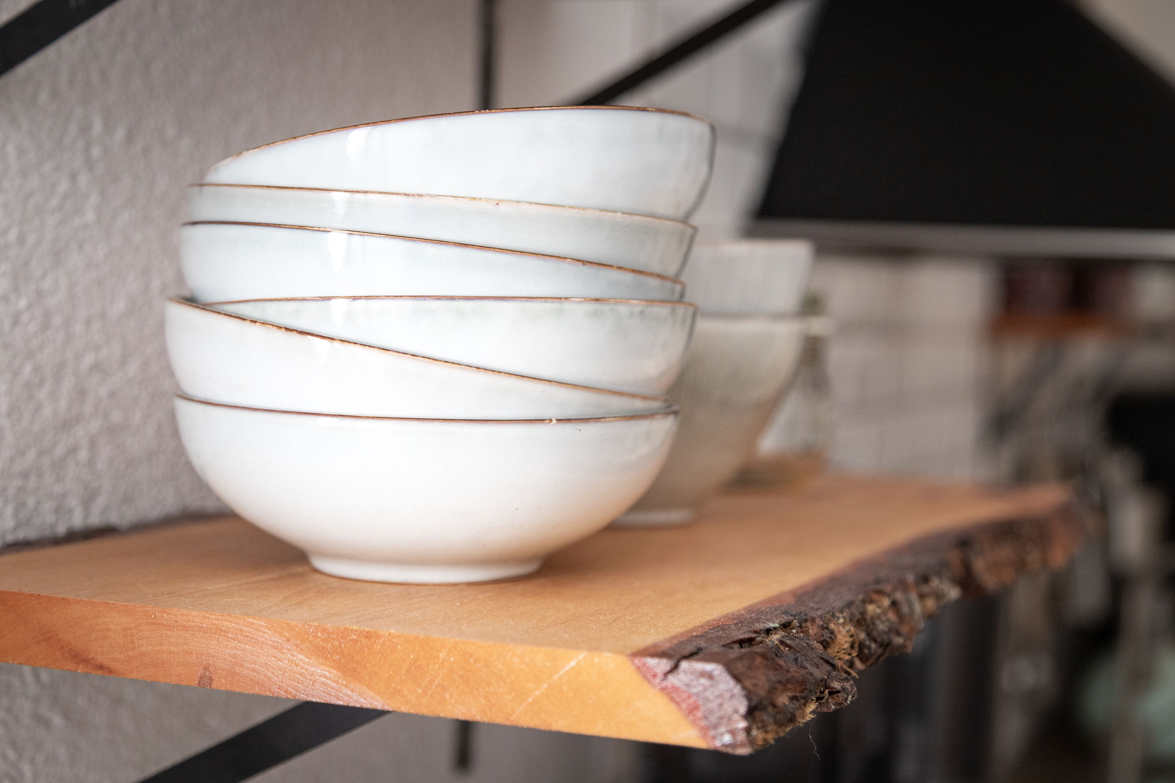 Un conjunto de tazones blancos con detalles dorados sobre un estante de madera.