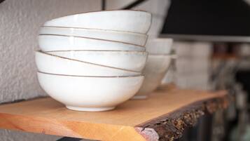 Un conjunto de tazones blancos con detalles dorados sobre un estante de madera.