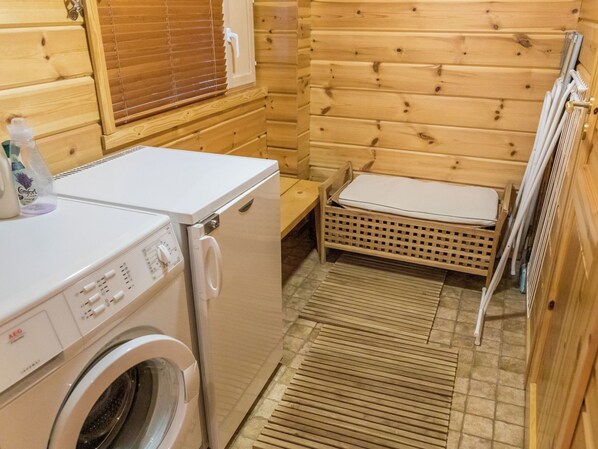 A compact, wooden cabin-style room with a washing machine, a small bench, and a radiator. - Ylläskaira a by Interhome (Äkäslompolo)