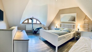Un dormitorio con techo inclinado, una cama, un escritorio, una silla, un ventanal y un televisor.