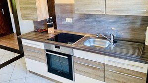 Una cocina moderna con horno empotrado, un lavabo y un bloque para cuchillos.